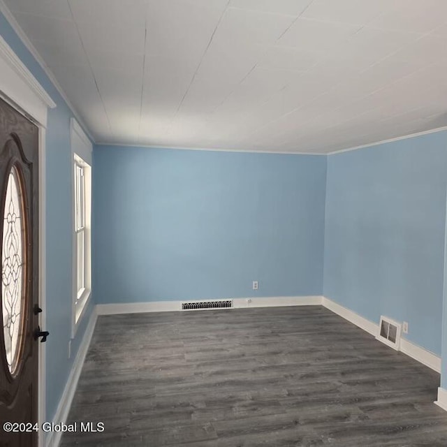 empty room with crown molding and dark wood-type flooring