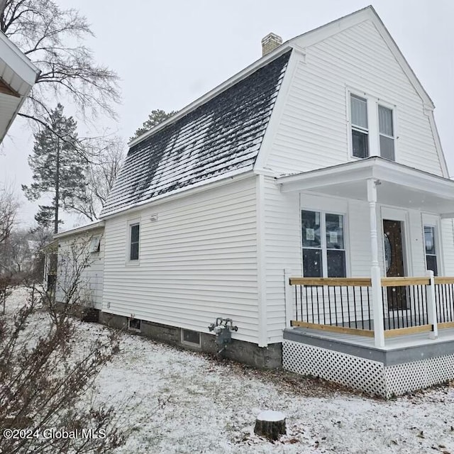 snow covered property with a porch