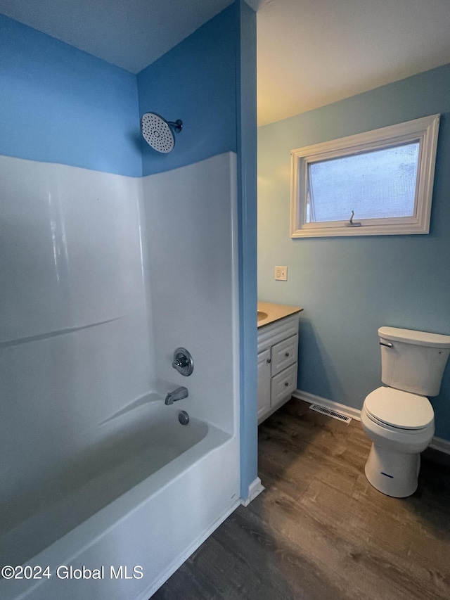 full bathroom featuring hardwood / wood-style flooring, vanity, toilet, and washtub / shower combination