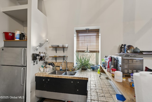 kitchen featuring backsplash, stainless steel fridge, sink, and tile countertops