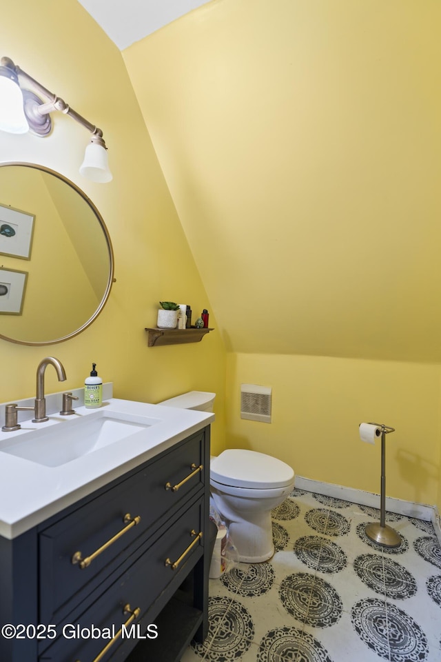 bathroom with toilet, vanity, and vaulted ceiling