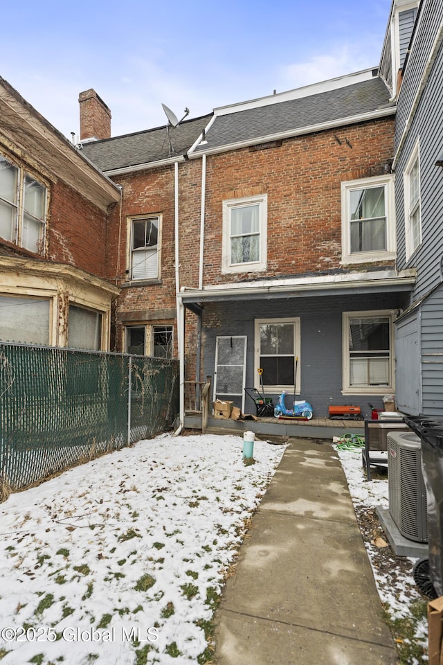 snow covered property with a porch and central AC