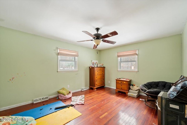 living area with a wealth of natural light, hardwood / wood-style floors, and ceiling fan