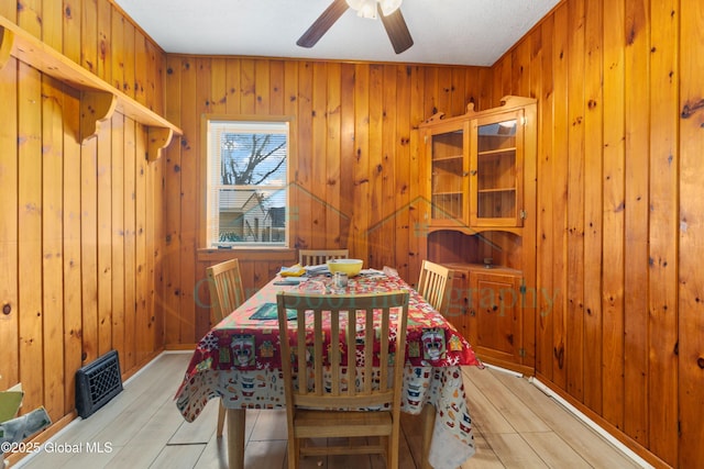 dining area featuring wood walls, ceiling fan, and light hardwood / wood-style floors