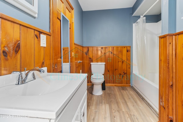 full bathroom with hardwood / wood-style floors, vanity, wood walls, toilet, and shower / bath combo with shower curtain