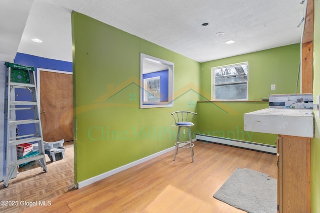 miscellaneous room featuring a textured ceiling, light wood-type flooring, and a baseboard heating unit