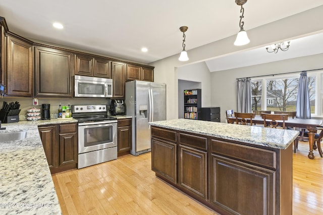 kitchen with light stone countertops, hanging light fixtures, stainless steel appliances, and dark brown cabinets