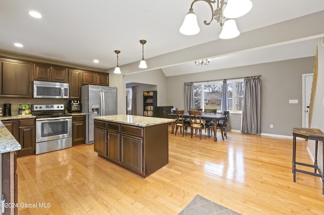 kitchen with a center island, decorative light fixtures, a notable chandelier, light stone counters, and stainless steel appliances