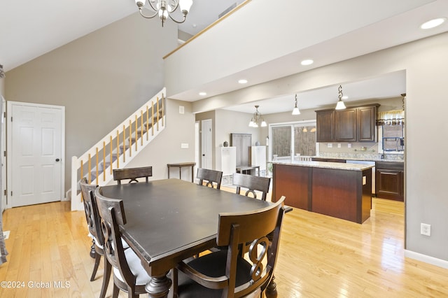 dining room featuring a notable chandelier, light wood-type flooring, and vaulted ceiling