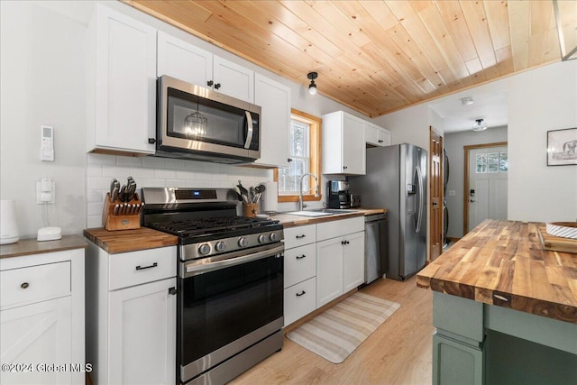 kitchen with butcher block counters, white cabinets, sink, appliances with stainless steel finishes, and wood ceiling