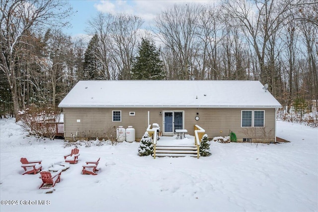 snow covered back of property with a deck