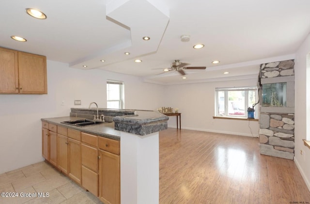 kitchen with ceiling fan, kitchen peninsula, sink, and light hardwood / wood-style flooring