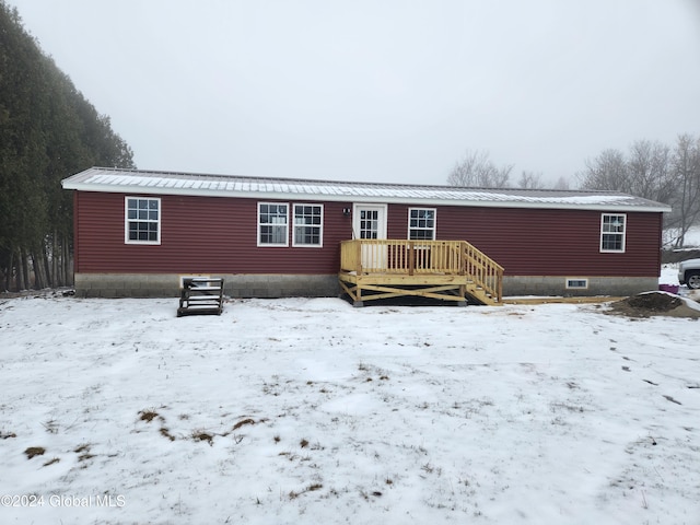 snow covered back of property featuring a deck