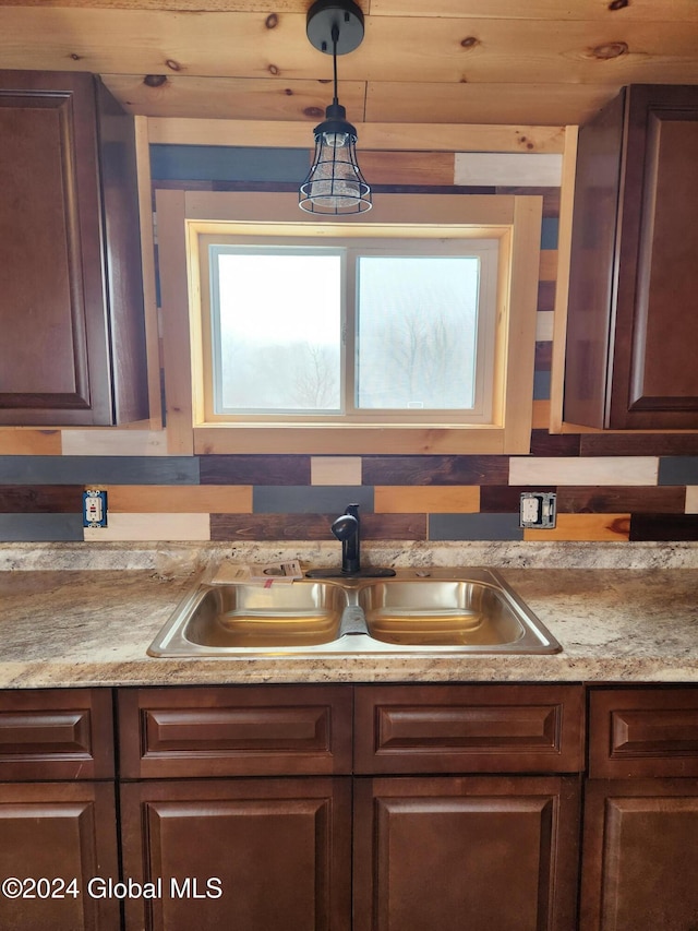 kitchen with pendant lighting, light stone countertops, wooden ceiling, and sink