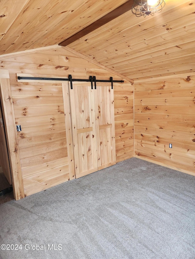 bonus room featuring carpet flooring, a barn door, wood walls, and lofted ceiling with beams