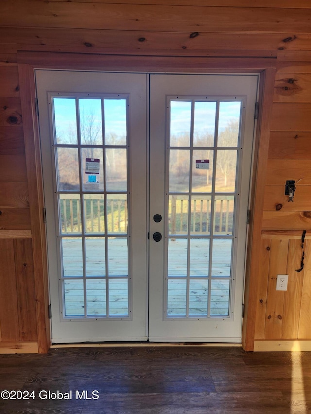 doorway with wooden walls, dark wood-type flooring, a wealth of natural light, and french doors