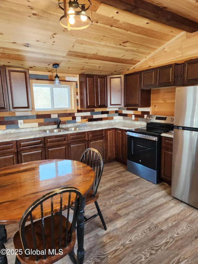 kitchen featuring vaulted ceiling with beams, light stone counters, appliances with stainless steel finishes, wood ceiling, and light wood-type flooring