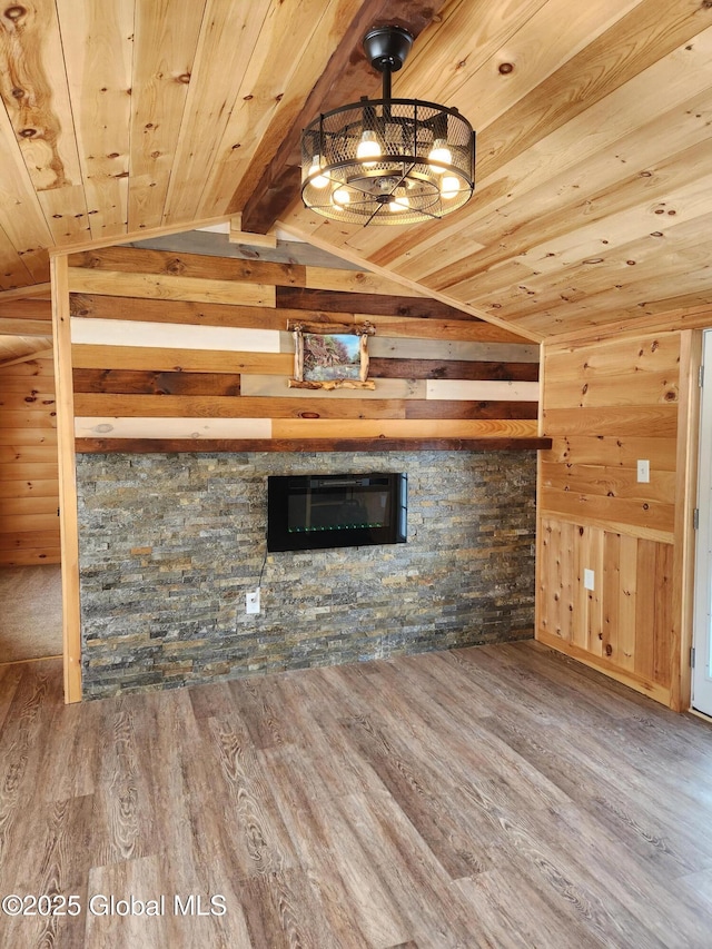 unfurnished living room featuring hardwood / wood-style floors, a stone fireplace, wooden walls, vaulted ceiling with beams, and wood ceiling