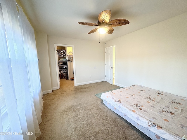 unfurnished bedroom featuring a closet, a spacious closet, ceiling fan, and light colored carpet