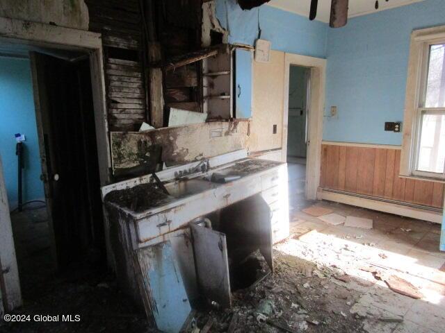 kitchen featuring a healthy amount of sunlight, wooden walls, and a baseboard radiator