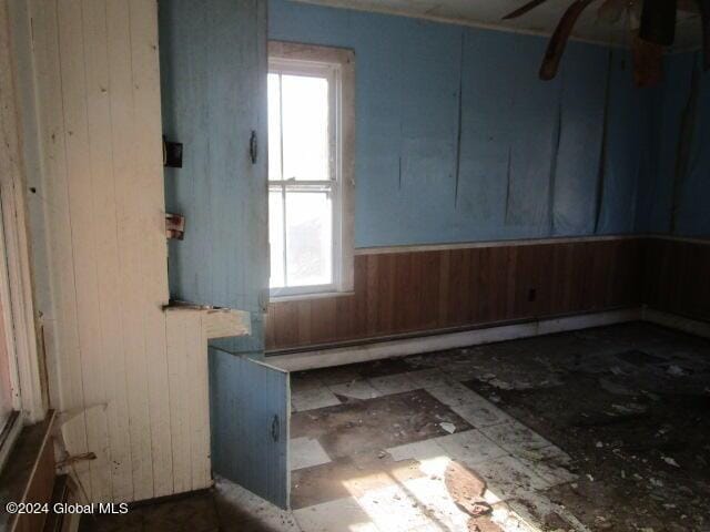 unfurnished room featuring a healthy amount of sunlight and wooden walls