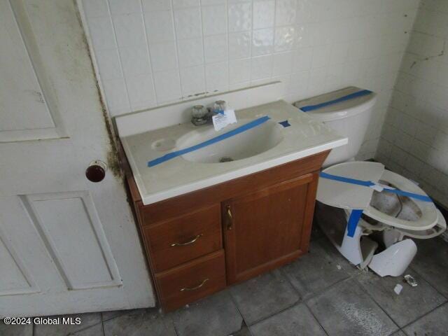 bathroom featuring vanity, tile walls, and toilet