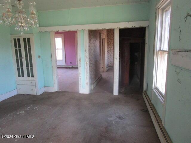 unfurnished room with a baseboard radiator and an inviting chandelier