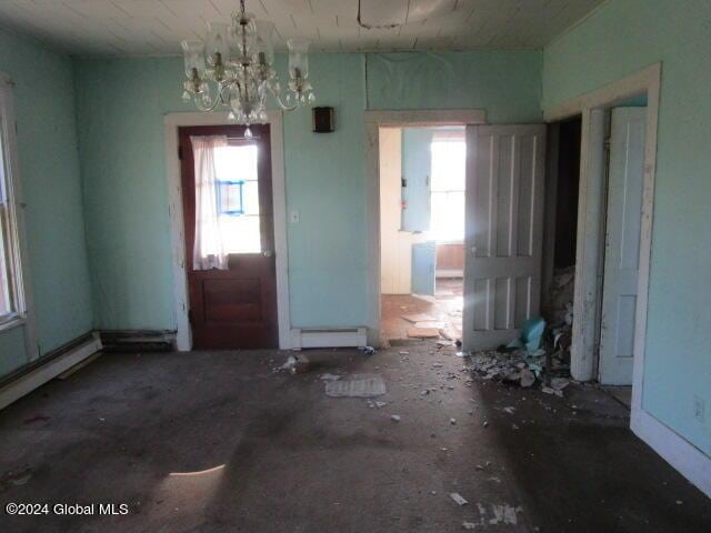 interior space with a notable chandelier, plenty of natural light, electric panel, and a baseboard radiator