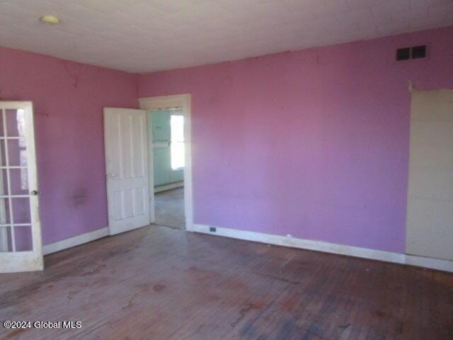 empty room with wood-type flooring and a baseboard heating unit