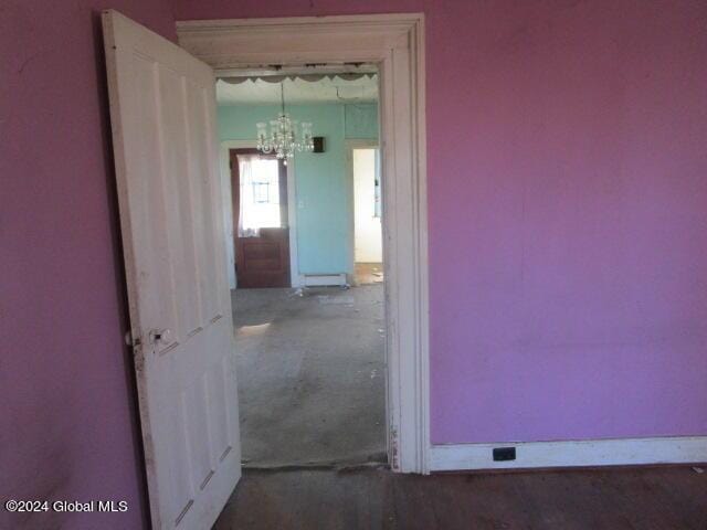 hall with baseboard heating and a chandelier