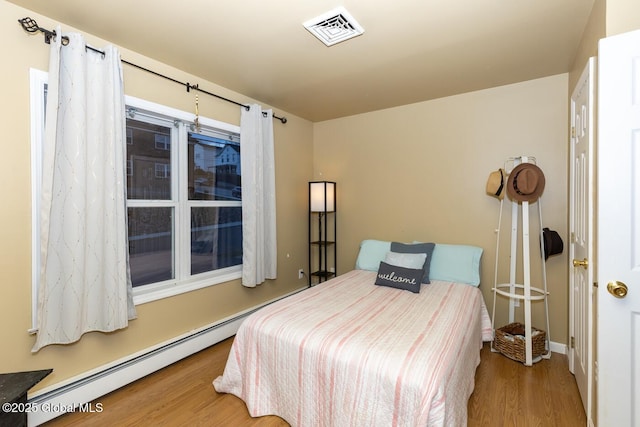 bedroom with light wood-type flooring and baseboard heating