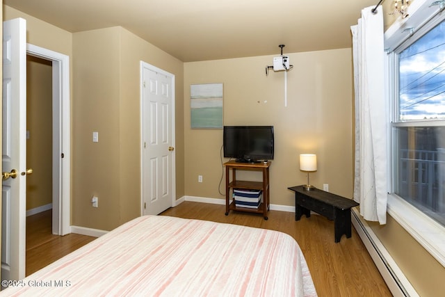 bedroom featuring baseboard heating, a closet, and light hardwood / wood-style floors