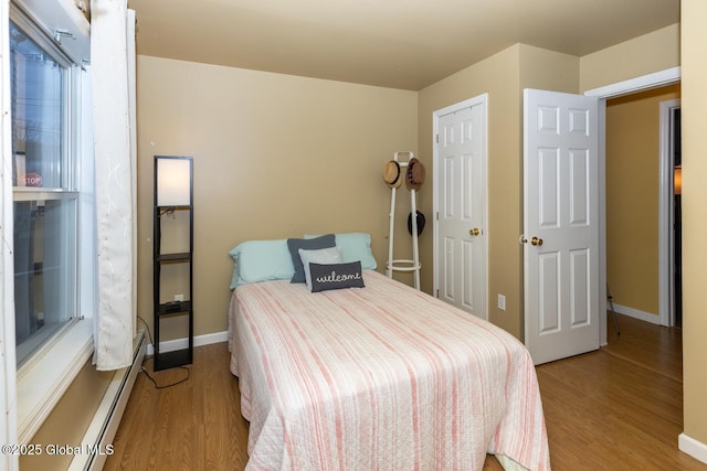 bedroom with a baseboard heating unit and light wood-type flooring