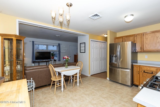 kitchen with a chandelier, stainless steel fridge, and pendant lighting