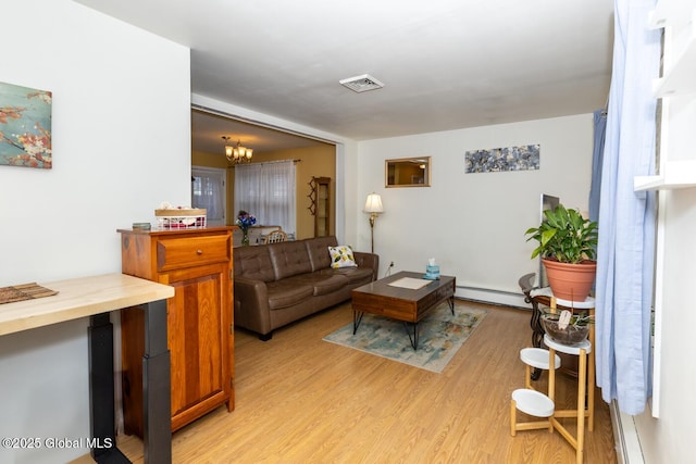 living room featuring light hardwood / wood-style floors, a baseboard heating unit, and a chandelier