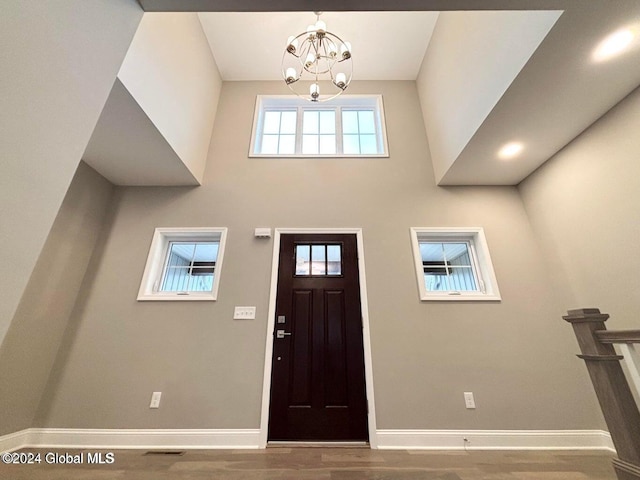 entrance foyer featuring a chandelier, wood-type flooring, and a high ceiling