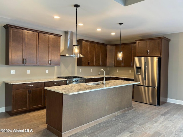 kitchen featuring sink, wall chimney range hood, pendant lighting, stainless steel fridge with ice dispenser, and light hardwood / wood-style floors