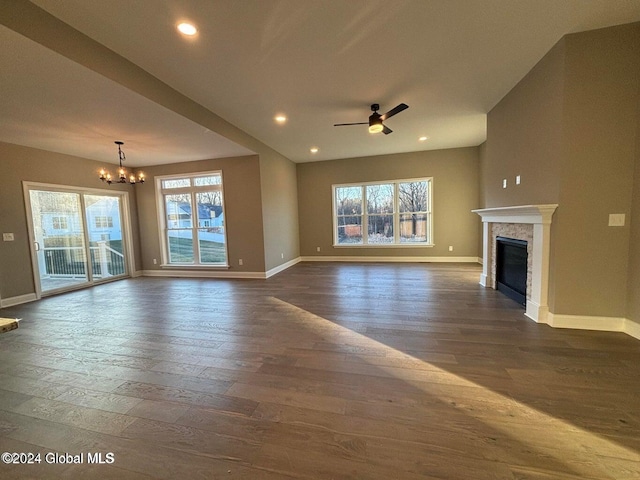 unfurnished living room featuring ceiling fan with notable chandelier and dark wood-type flooring