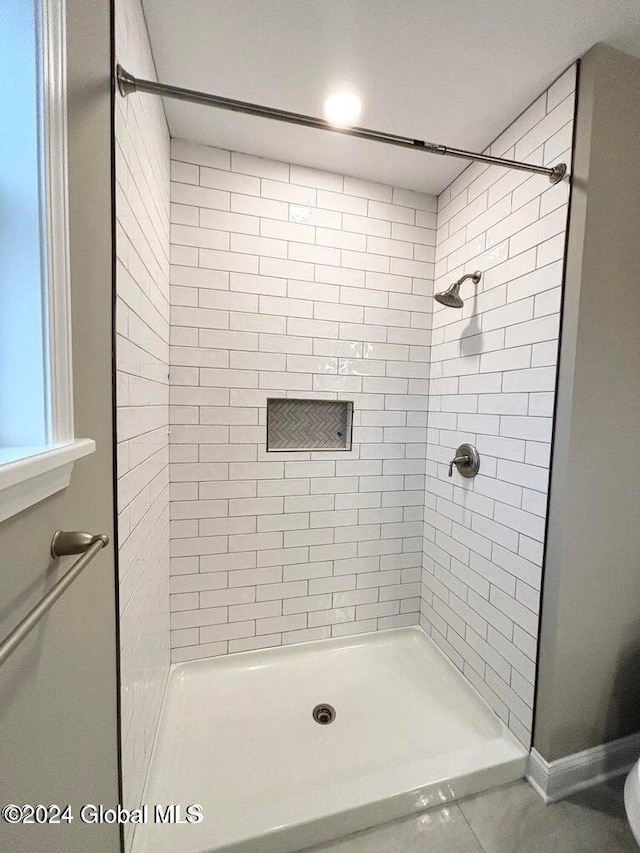 bathroom featuring a tile shower and tile patterned flooring