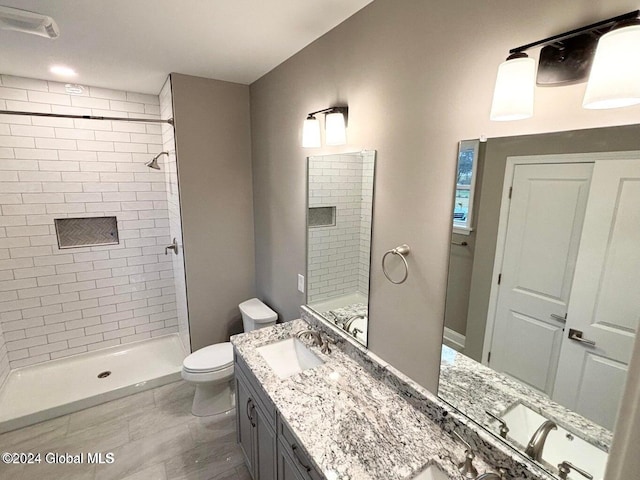 bathroom featuring vanity, toilet, and tiled shower