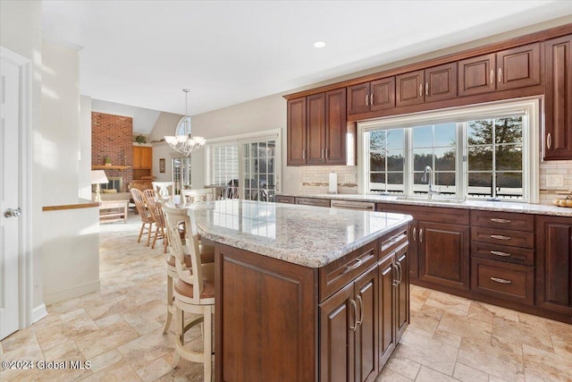 kitchen featuring decorative backsplash, sink, pendant lighting, a chandelier, and a kitchen island