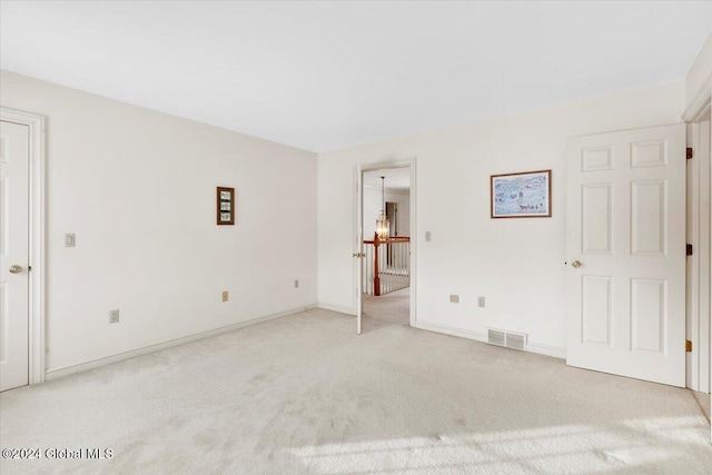 carpeted empty room featuring a notable chandelier