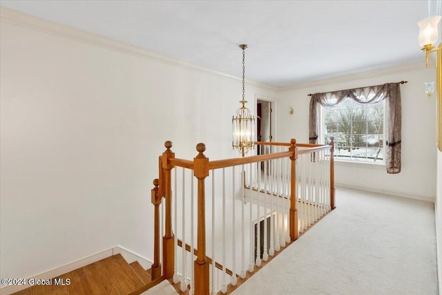 corridor with carpet, ornamental molding, and a notable chandelier