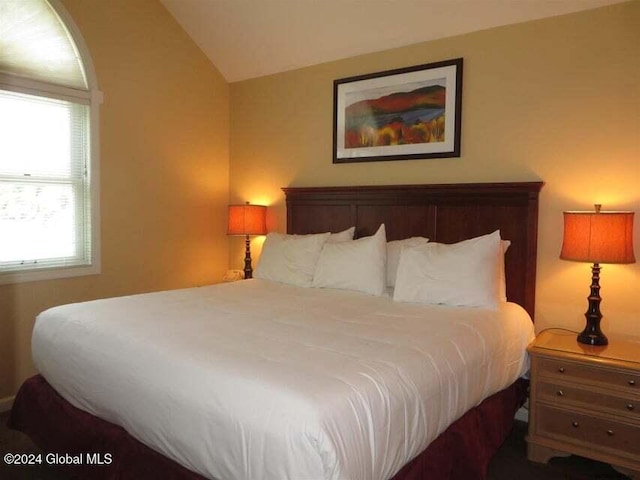 bedroom with vaulted ceiling and multiple windows