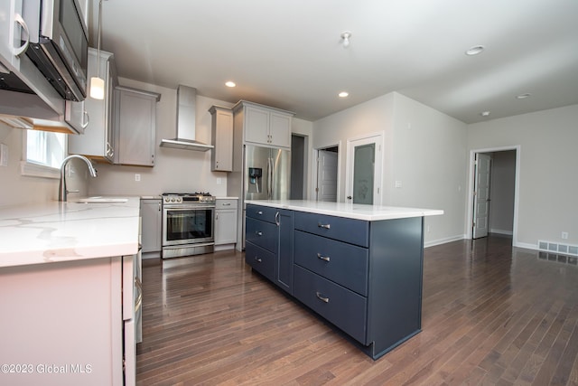 kitchen with sink, stainless steel appliances, wall chimney range hood, dark hardwood / wood-style flooring, and a kitchen island