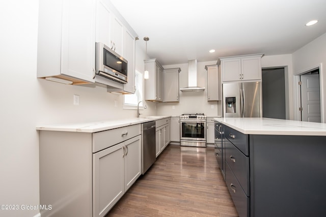 kitchen with appliances with stainless steel finishes, dark hardwood / wood-style flooring, wall chimney exhaust hood, gray cabinetry, and decorative light fixtures