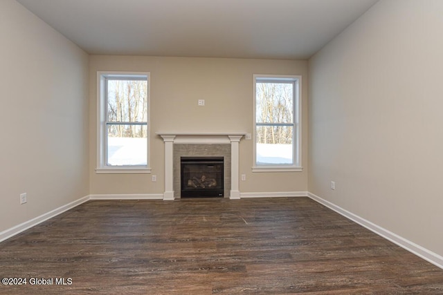 unfurnished living room with dark hardwood / wood-style floors and a tiled fireplace