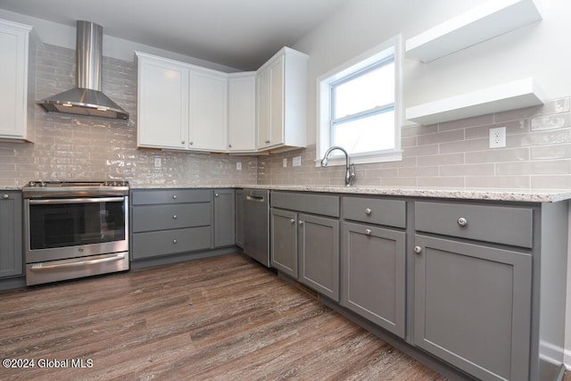 kitchen with gray cabinets, appliances with stainless steel finishes, white cabinetry, dark wood-type flooring, and wall chimney exhaust hood