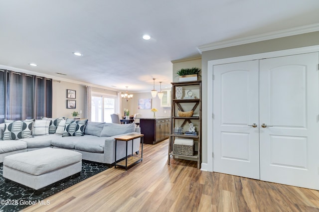 living room featuring ornamental molding, an inviting chandelier, and light hardwood / wood-style floors