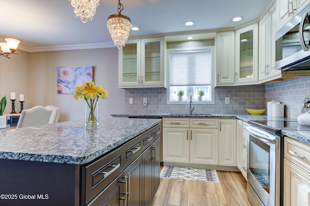 kitchen with light hardwood / wood-style flooring, a chandelier, decorative light fixtures, appliances with stainless steel finishes, and sink